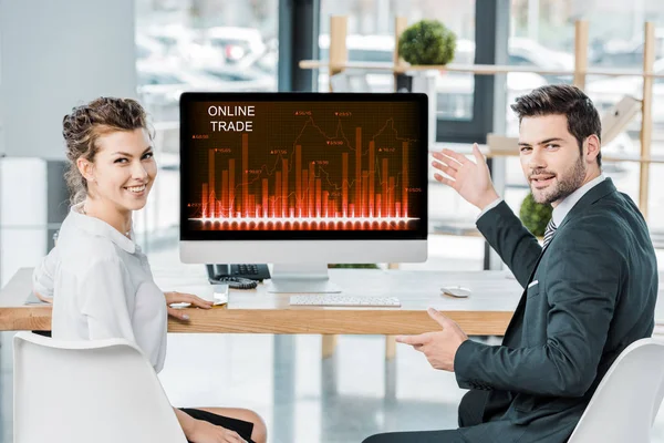 Colegas de negocios sonrientes en el lugar de trabajo con pantalla de computadora con letras comerciales en línea en la oficina — Stock Photo