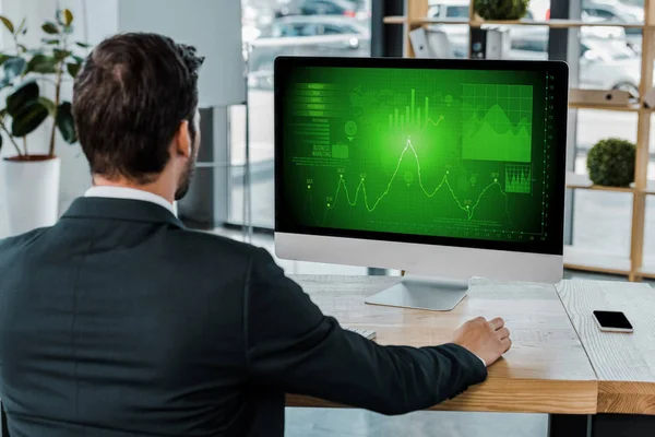 Vue arrière de l'homme d'affaires sur le lieu de travail avec écran d'ordinateur avec diagramme dans le bureau — Photo de stock