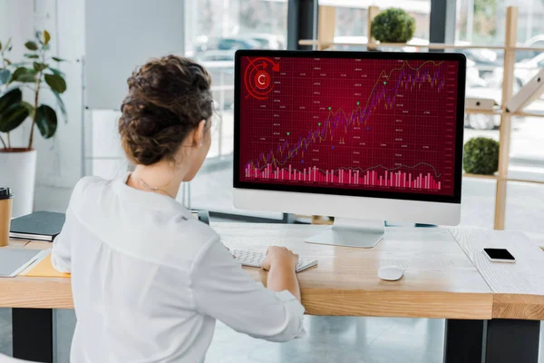 Rückseite der Geschäftsfrau, die im Büro am Computer mit Grafik arbeitet — Stockfoto