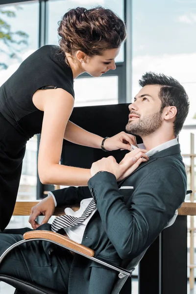 Vista laterale della giovane imprenditrice sbottonatura colleghi camicia sul posto di lavoro in ufficio — Foto stock