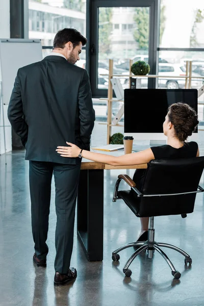 Vista posterior de la mujer de negocios coqueteando con su colega en la oficina - foto de stock