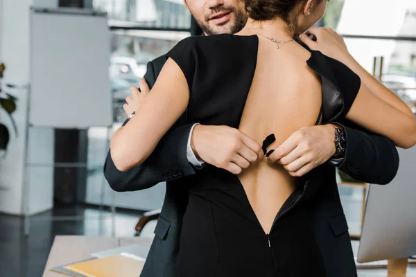 Partial view of businessman unbuttoning bra of businesswoman in office — Stock Photo