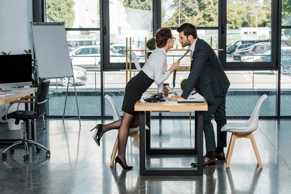 Боковой вид бизнесмена и бизнесвумен, листающих на рабочем месте в офисе — стоковое фото