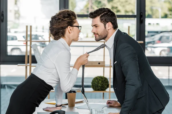 Вид збоку бізнесмена і бізнес-леді фліртують на робочому місці в офісі — стокове фото