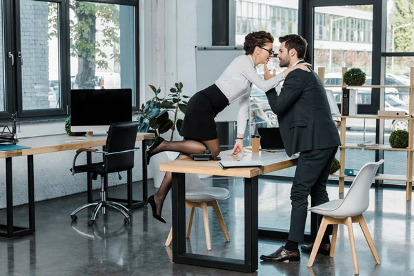 Seitenansicht eines Geschäftsmannes und einer Geschäftsfrau, die am Arbeitsplatz im Büro flirten — Stockfoto