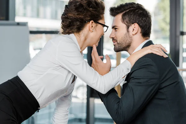 Seitenansicht eines Geschäftsmannes und einer Geschäftsfrau, die im Büro flirten — Stockfoto