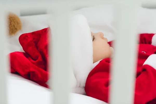 Gros plan du petit bébé en costume de Père Noël couché dans le lit du bébé — Photo de stock