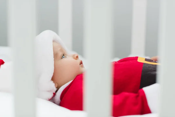 Primer plano de lindo bebé en traje de santa acostado en cuna - foto de stock