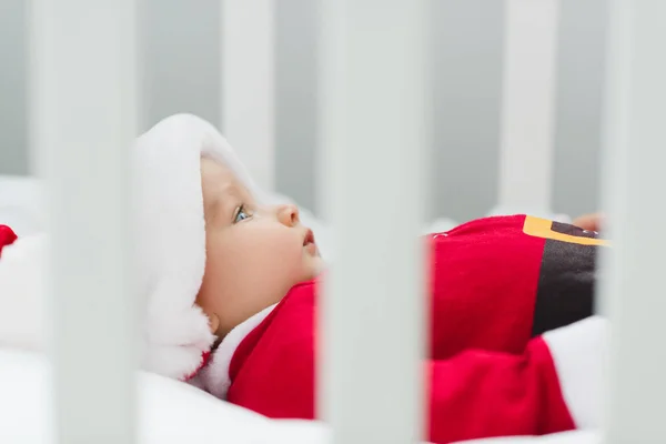 Close-up shot of cute little baby in santa suit lying in crib — Stock Photo