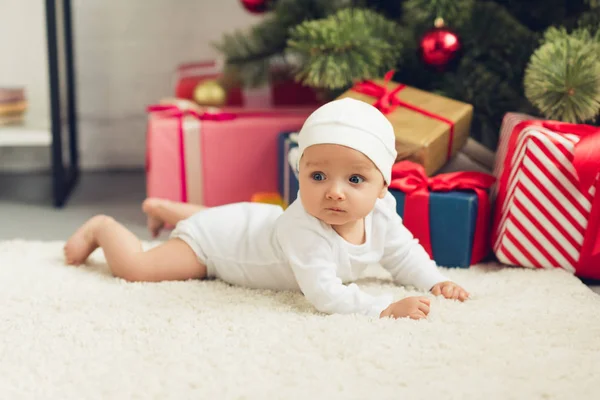 Beautiful little baby lying on floor with christmas gifts — Stock Photo