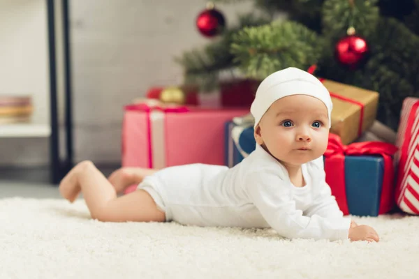 Adorable little baby lying on floor with christmas gifts — Stock Photo