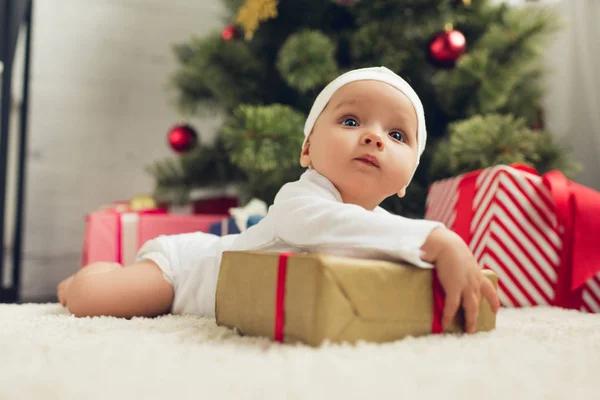 Lindo pequeño bebé acostado en el suelo con regalos de Navidad - foto de stock
