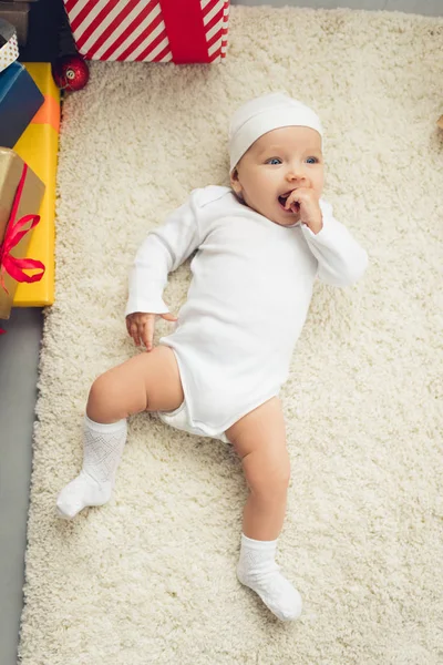 Adorable little baby lying on floor with gift boxes — Stock Photo