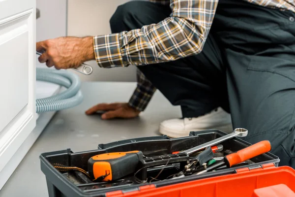 Immagine ritagliata di idraulico riparazione lavandino rotto in cucina — Foto stock