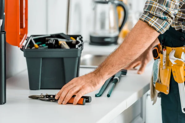 Image recadrée de plombier mettre des outils sur le comptoir de cuisine dans la cuisine — Photo de stock