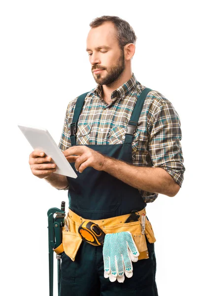 Handsome plumber with tool belt using tablet isolated on white — Stock Photo