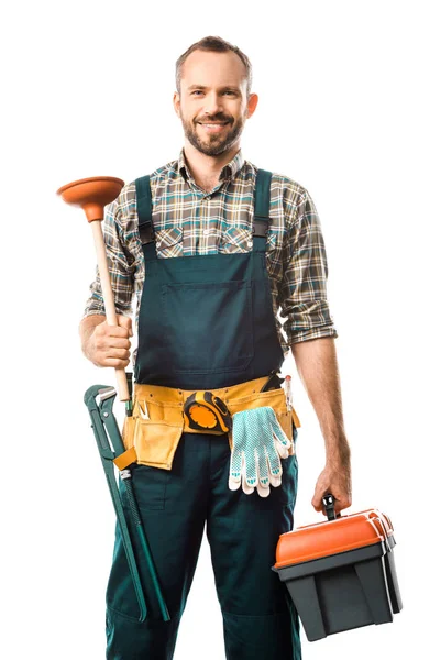 Smiling handsome plumber holding plunger and toolbox isolated on white, looking at camera — Stock Photo