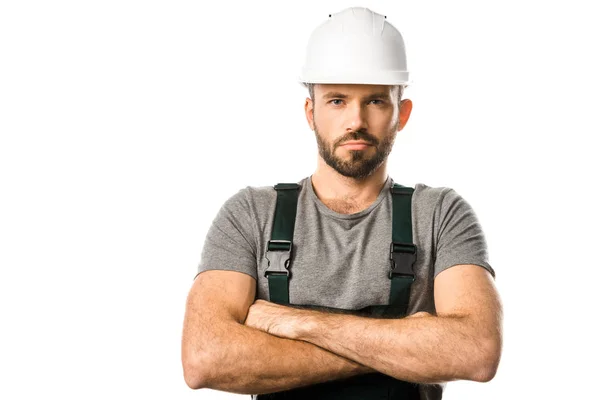 Handsome plumber in helmet standing with crossed arms and looking at camera isolated on white — Stock Photo