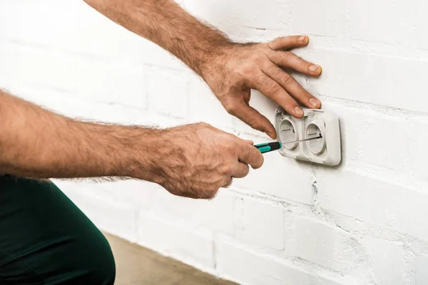 Cropped image of electrician repairing power socket with screwdriver at home — Stock Photo