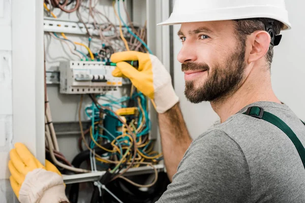 Eletricista alegre bonito reparando caixa elétrica e usando chave de fenda no corredor — Fotografia de Stock