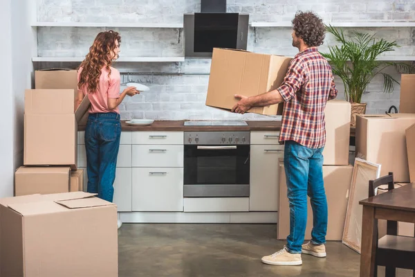 Namorado e namorada desempacotando utensílio de caixas de papelão juntos na nova cozinha — Fotografia de Stock