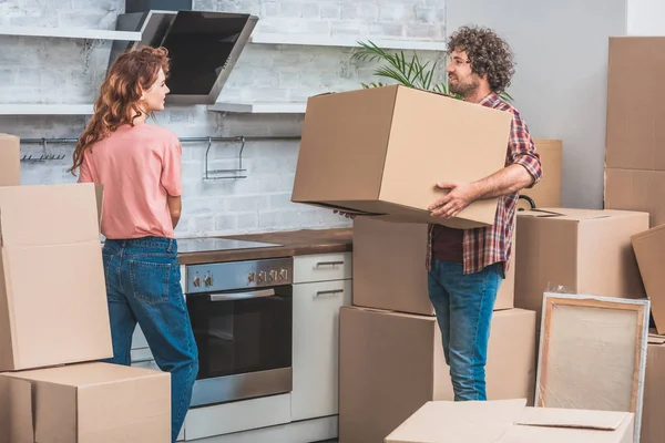 Pareja desembalaje cajas de cartón juntos en la nueva cocina - foto de stock