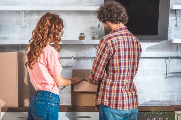 Back view of couple unpacking cardboard box in new kitchen — Stock Photo