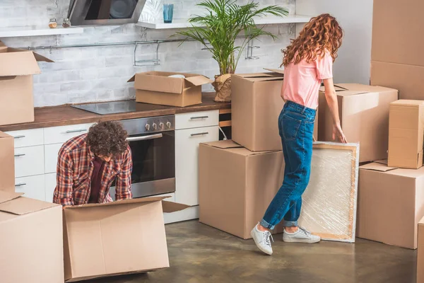 Casal com cabelo encaracolado desempacotar caixas de papelão em nova casa — Fotografia de Stock