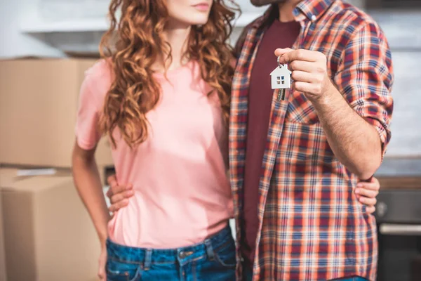 Cropped image of couple holding house trinket with keys at new home — Stock Photo
