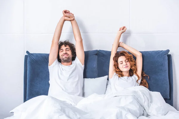 Hermosa feliz joven pareja despertando juntos en la cama - foto de stock