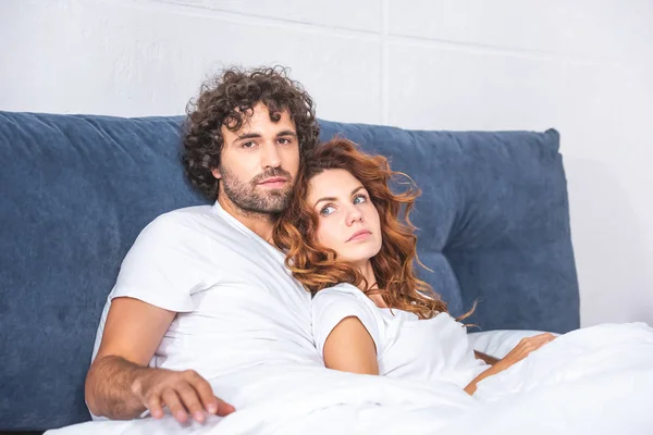 Красивая молодая пара, лежащая вместе на кровати, мужчина смотрит в камеру — стоковое фото