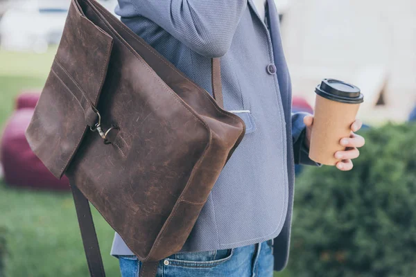 Vista ritagliata di uomo con zaino in pelle che tiene monouso tazza di caffè — Foto stock