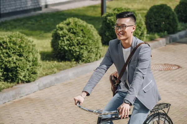 Smiling asian man riding bicycle in park — Stock Photo