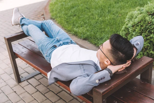 Стильний чоловік у сірій куртці відпочиває на лавці — стокове фото