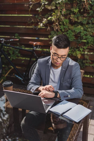Asiático empresário verificando tempo enquanto remoto trabalhando no café — Fotografia de Stock