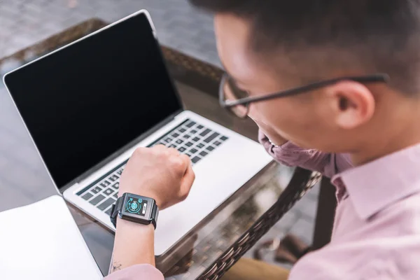 Selective focus of asian man checking time while remote working at tabletop — Stock Photo