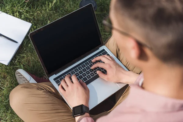 Foyer sélectif de pigiste à l'aide d'un ordinateur portable avec écran blanc sur l'herbe verte dans le parc — Photo de stock