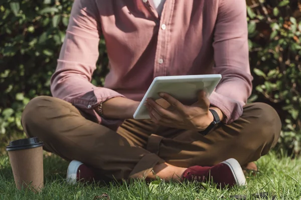 Обрезанный снимок человека с помощью цифрового планшета в парке — стоковое фото