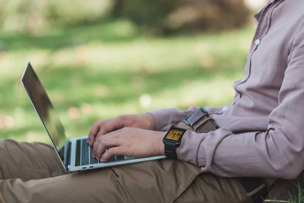 Обрезанный снимок фрилансера, работающего на ноутбуке в парке — стоковое фото