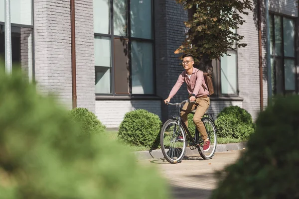 Asiatischer junger Mann mit Rucksack fährt Fahrrad auf Straße — Stockfoto