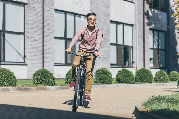 Asiático joven hombre con mochila a caballo bicicleta en calle - foto de stock