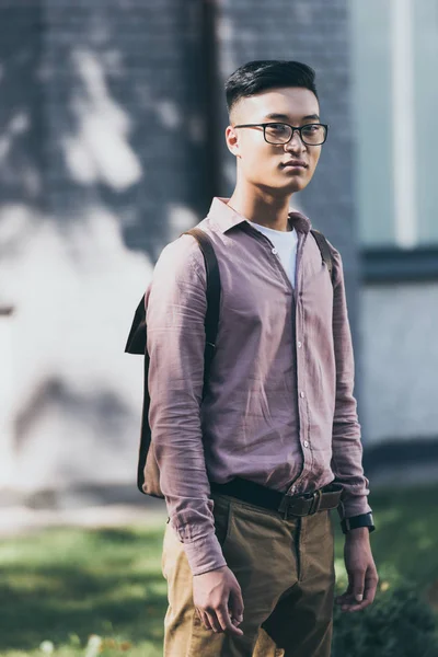 Portrait of pensive asian man in eyeglasses looking at camera on street — Stock Photo