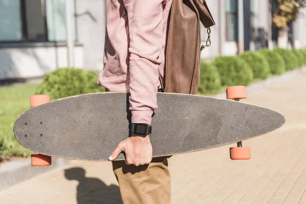 Visão parcial do homem com mochila segurando longboard na rua — Fotografia de Stock