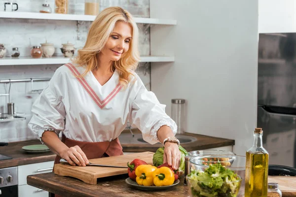 Bionda donna adulta preparare insalata per la cena a casa — Foto stock