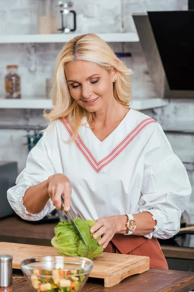 Attraktive erwachsene Frau bereitet Salat für das Abendessen zu und schneidet Kohl zu Hause — Stockfoto