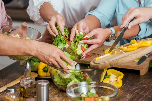 Imagem cortada de amigos maduros preparando salada para o jantar em casa — Fotografia de Stock