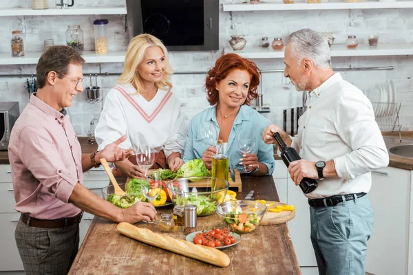 Sorridenti vecchi amici che preparano insalata per cena e celebrano l'incontro a casa — Foto stock