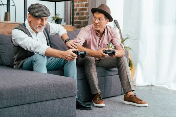 Emotional mature male friends playing with joysticks at home — Stock Photo