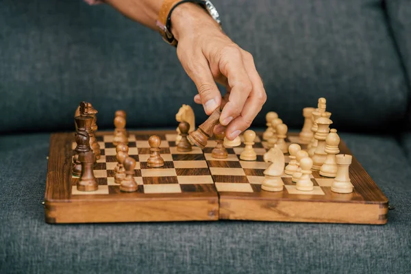 Primer plano vista parcial de hombre jugando ajedrez en sofá - foto de stock