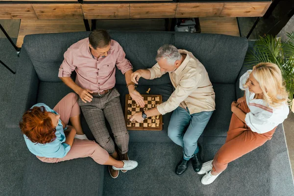 Blick auf alte Freunde, die auf der Couch sitzen und zu Hause Schach spielen — Stockfoto